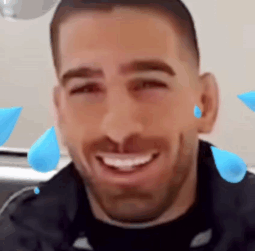 A Man With A Beard Is Smiling With Blue Drops Of Water On His Face . GIF