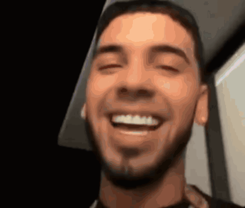 A Man With A Beard Is Smiling With His Eyes Closed And His Mouth Open GIF