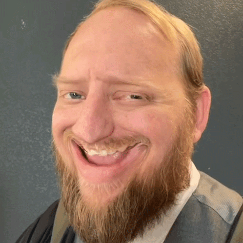 A Man With A Beard Is Smiling With His Tongue Sticking Out GIF