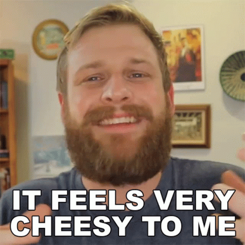 A Man With A Beard Is Smiling With The Words It Feels Very Cheesy To Me Below Him GIF