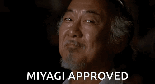 A Man With A Beard Is Smiling With The Words `` Miyagi Approved '' Behind Him . GIF
