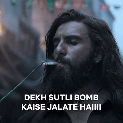 A Man With A Beard Is Smoking A Cigarette And Says " Dekh Sutli Bomb " GIF