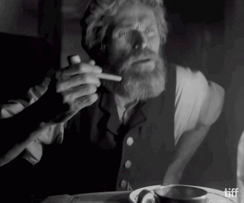 A Man With A Beard Is Smoking A Cigarette In A Black And White Photo .. GIF