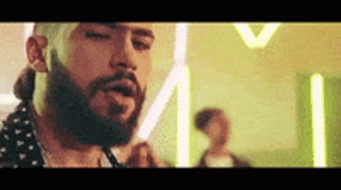 A Man With A Beard Is Smoking A Cigarette In A Room With Neon Lights . GIF