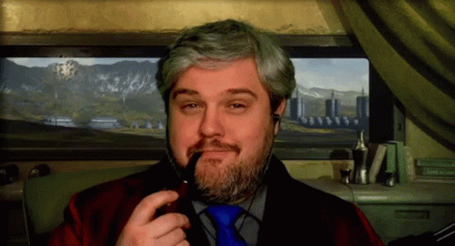 A Man With A Beard Is Smoking A Pipe In Front Of A Picture Of Mountains GIF