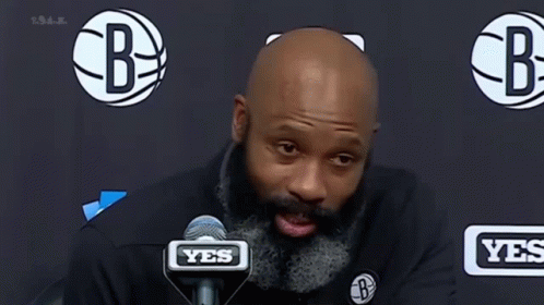A Man With A Beard Is Speaking Into A Microphone . GIF