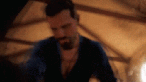 A Man With A Beard Is Standing In A Dark Room In A Dark Room . GIF