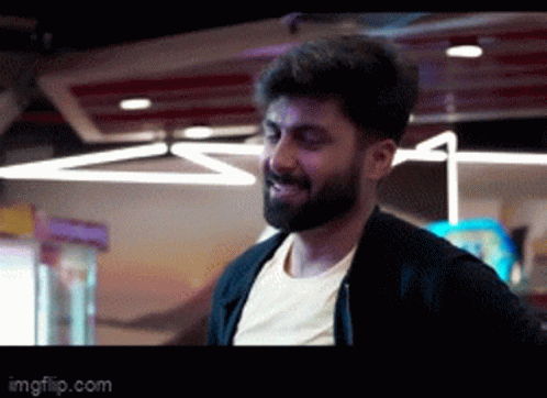 a man with a beard is standing in a dark room .