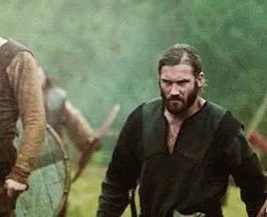 A Man With A Beard Is Standing In A Field Looking At Something GIF