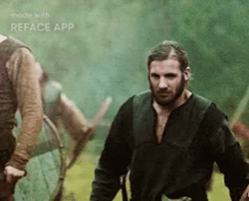 A Man With A Beard Is Standing In A Field With Other Men . GIF