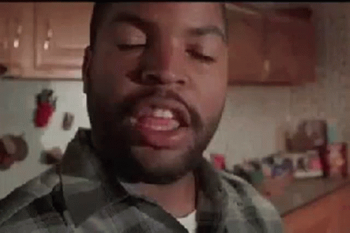 A Man With A Beard Is Standing In A Kitchen With His Eyes Closed And His Mouth Open . GIF