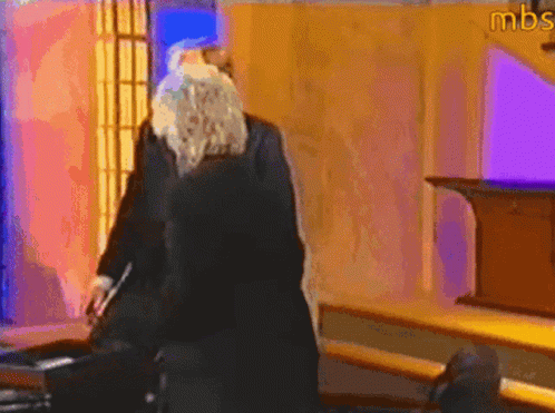 A Man With A Beard Is Standing In A Room With Mbs Written On The Wall GIF