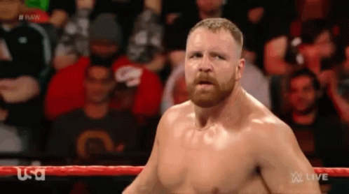 A Man With A Beard Is Standing In A Wrestling Ring With A Crowd Behind Him . GIF