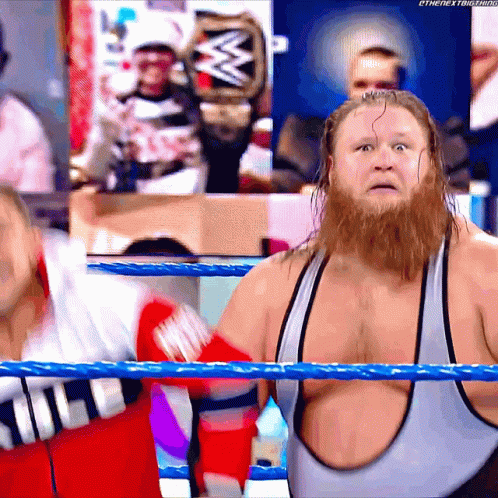A Man With A Beard Is Standing In A Wrestling Ring With A W Logo In The Background GIF