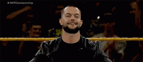 A Man With A Beard Is Standing In A Wrestling Ring With His Arms Outstretched . GIF
