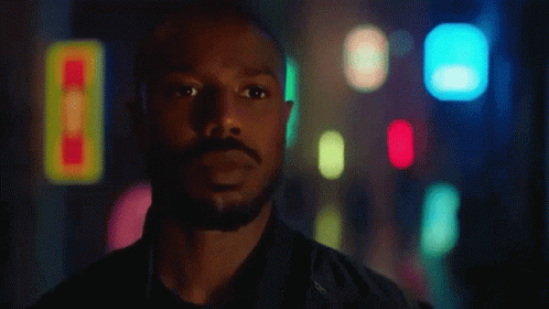 A Man With A Beard Is Standing In Front Of A Blurry Background With His Eyes Closed . GIF