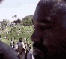 A Man With A Beard Is Standing In Front Of A Crowd . GIF