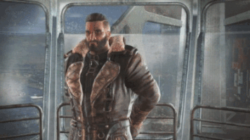 A Man With A Beard Is Standing In Front Of A Glass Door GIF
