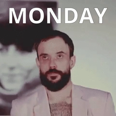 a man with a beard is standing in front of a monday poster