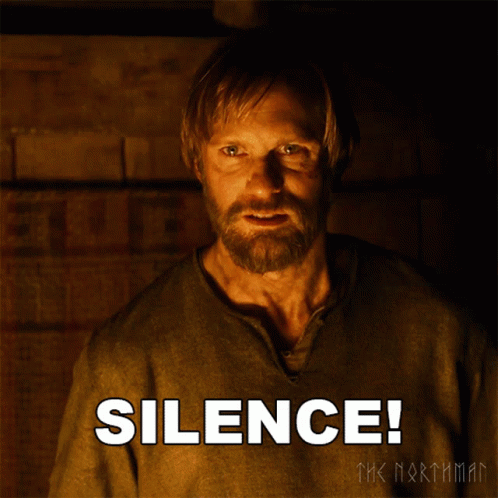 A Man With A Beard Is Standing In Front Of A Poster That Says Silence GIF