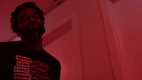 A Man With A Beard Is Standing In Front Of A Red Door GIF