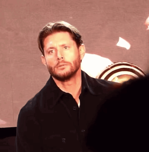 A Man With A Beard Is Standing In Front Of A Screen GIF