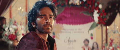 A Man With A Beard Is Standing In Front Of A Sign That Says ' Ayaan ' On It GIF