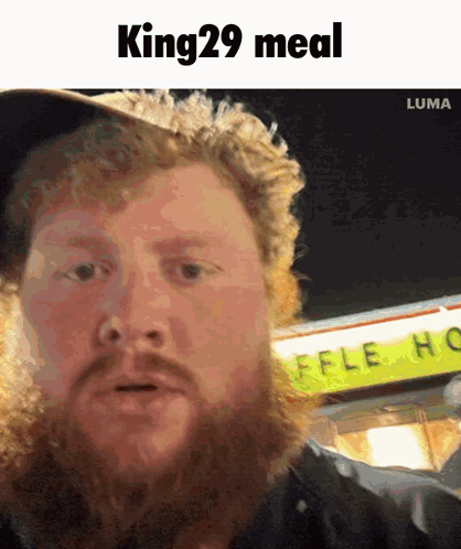 A Man With A Beard Is Standing In Front Of A Sign That Says King 29 Meal GIF