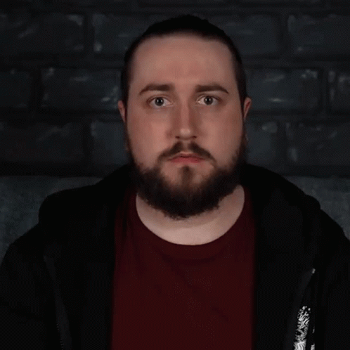 A Man With A Beard Is Standing In Front Of A Sign That Says " Lovely " GIF