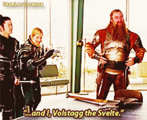 A Man With A Beard Is Standing In Front Of A Table With The Words " And I Volstagg The Svelte " GIF