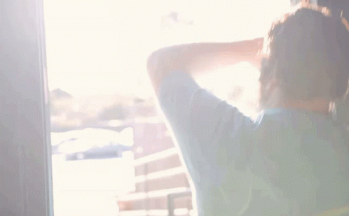 A Man With A Beard Is Standing In Front Of A Wall And Covering His Face With His Hand GIF