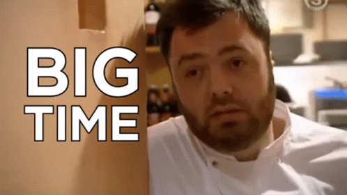A Man With A Beard Is Standing In Front Of A Wall That Says Big Time GIF
