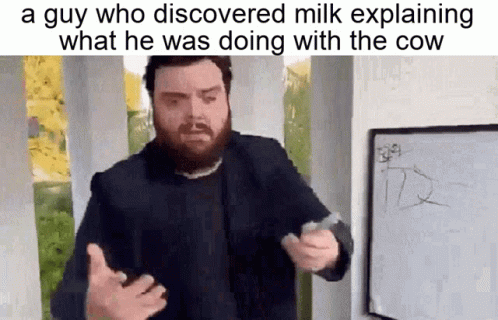A Man With A Beard Is Standing In Front Of A Whiteboard Explaining What He Was Doing With The Cow . GIF