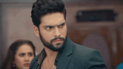 A Man With A Beard Is Standing In Front Of A Woman In A Room . GIF