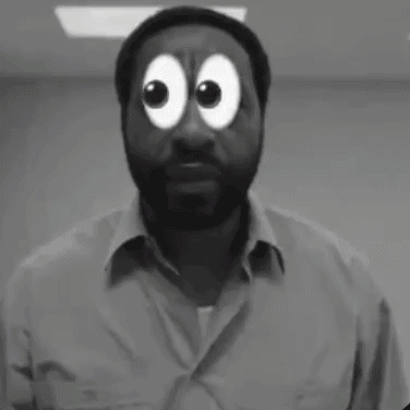 A Man With A Beard Is Standing In Front Of A Yellow Wall And Making A Funny Face . GIF