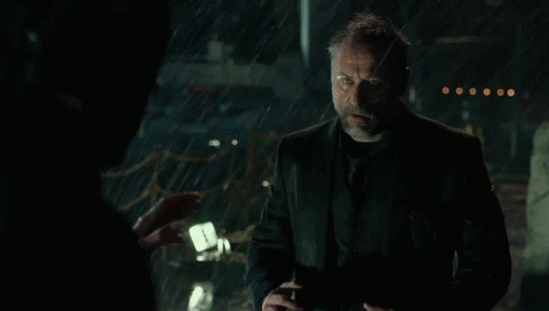 a man with a beard is standing in the rain with his mouth open .