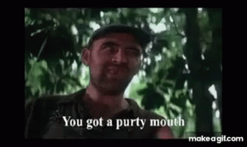 A Man With A Beard Is Standing In The Woods And Talking To Someone . GIF