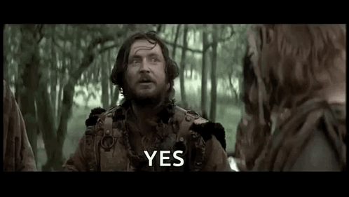 A Man With A Beard Is Standing In The Woods Talking To A Group Of People . GIF