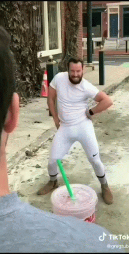 A Man With A Beard Is Standing Next To A Cup Of Drink With A Straw . GIF
