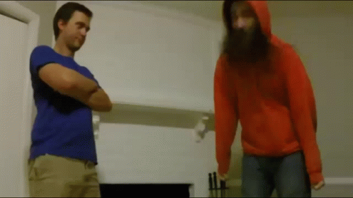 A Man With A Beard Is Standing Next To A Woman In An Orange Hoodie GIF