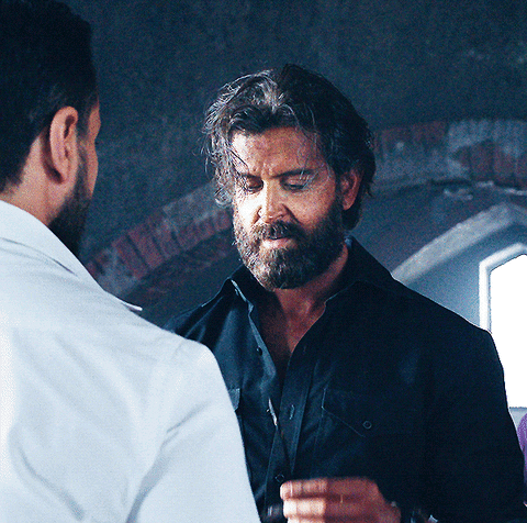 A Man With A Beard Is Standing Next To Another Man GIF