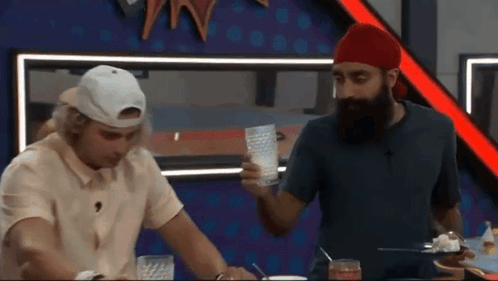 a man with a beard is standing next to another man who is holding a glass