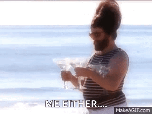 A Man With A Beard Is Standing On The Beach Holding A Martini And Says Me Either GIF