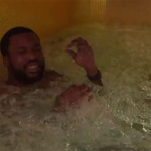 A Man With A Beard Is Taking A Bath In A Bathtub GIF