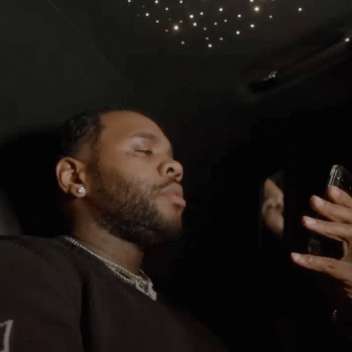 A Man With A Beard Is Taking A Picture Of Himself In A Mirror With His Cell Phone . GIF