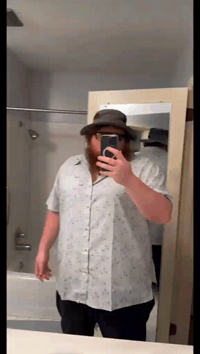 A Man With A Beard Is Taking A Selfie In Front Of A Mirror GIF