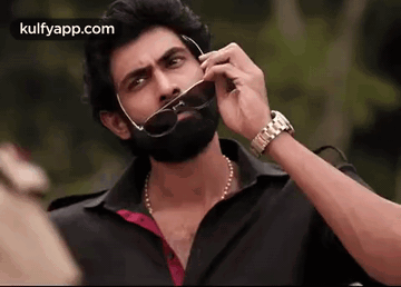 A Man With A Beard Is Talking On A Cell Phone While Wearing Sunglasses . GIF