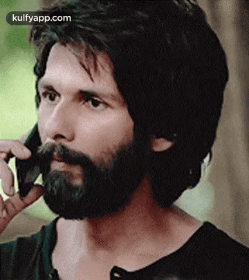 A Man With A Beard Is Talking On A Phone . GIF