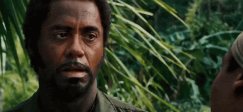 A Man With A Beard Is Talking To Another Man In A Forest . GIF