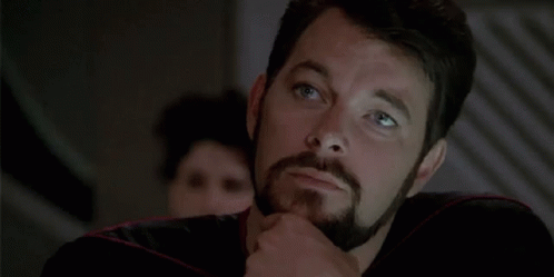A Man With A Beard Is Thinking And Pointing To His Chin . GIF